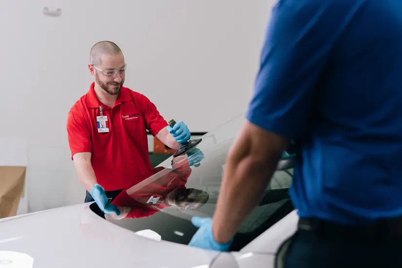 Two Glass Doctor specialists replacing a new windshield into a car
